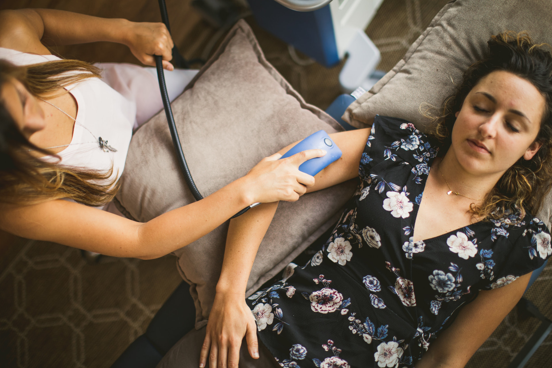 Practitioner running a PEMF applicator along a guest's arm while she rests