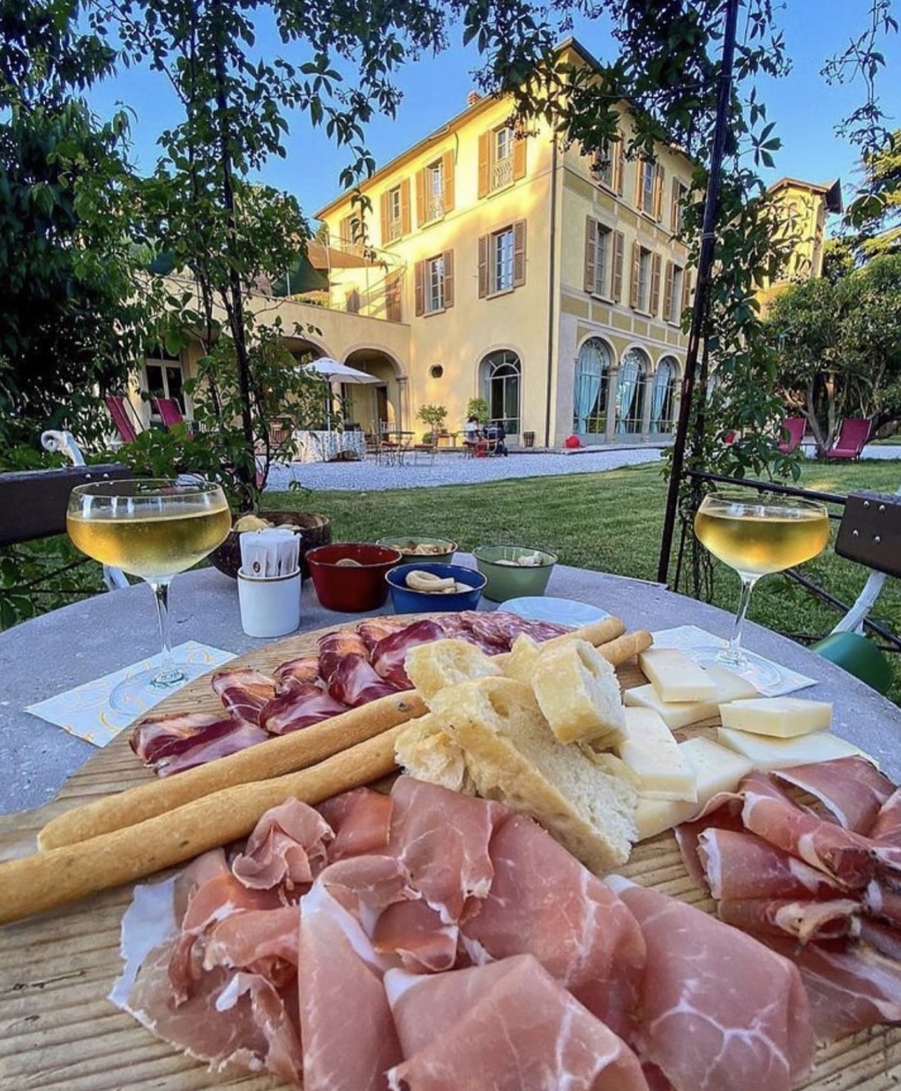 Aperitivo board and wine on a garden table in front of the villa at dusk