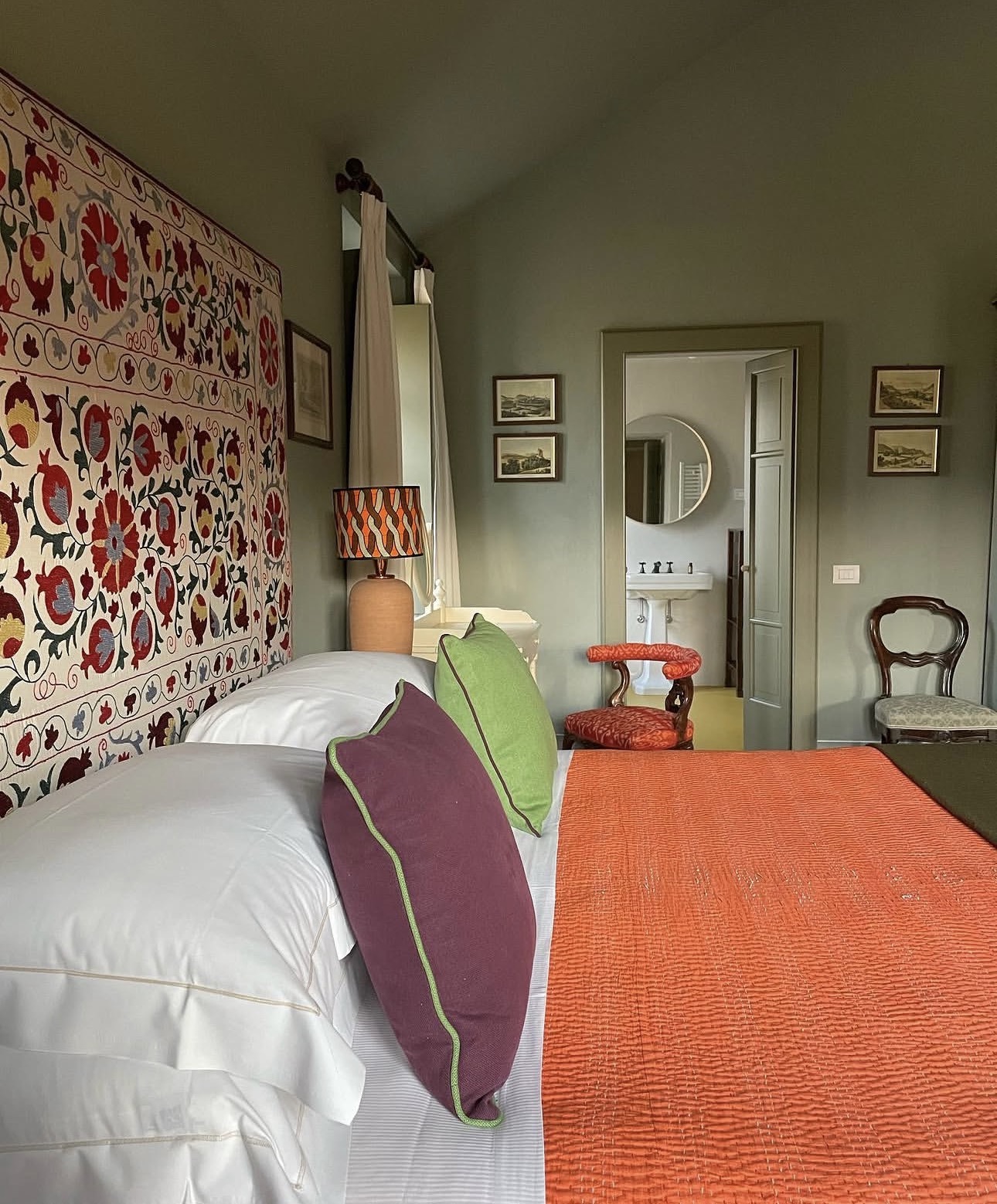 Guest suite with suzani headboard, orange quilt, and an ensuite bathroom beyond