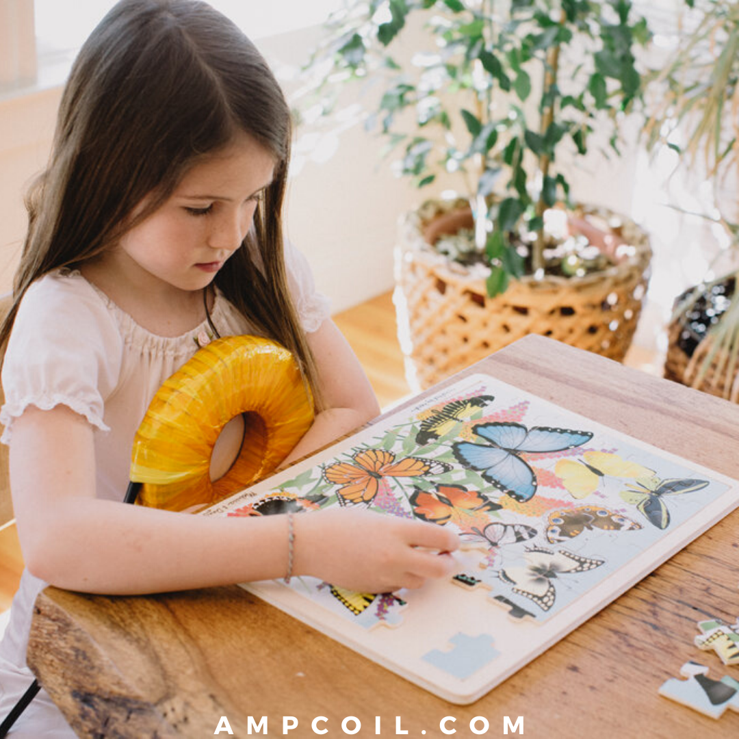 Young guest resting against a gold AmpCoil petal coil while doing a puzzle at a wooden table