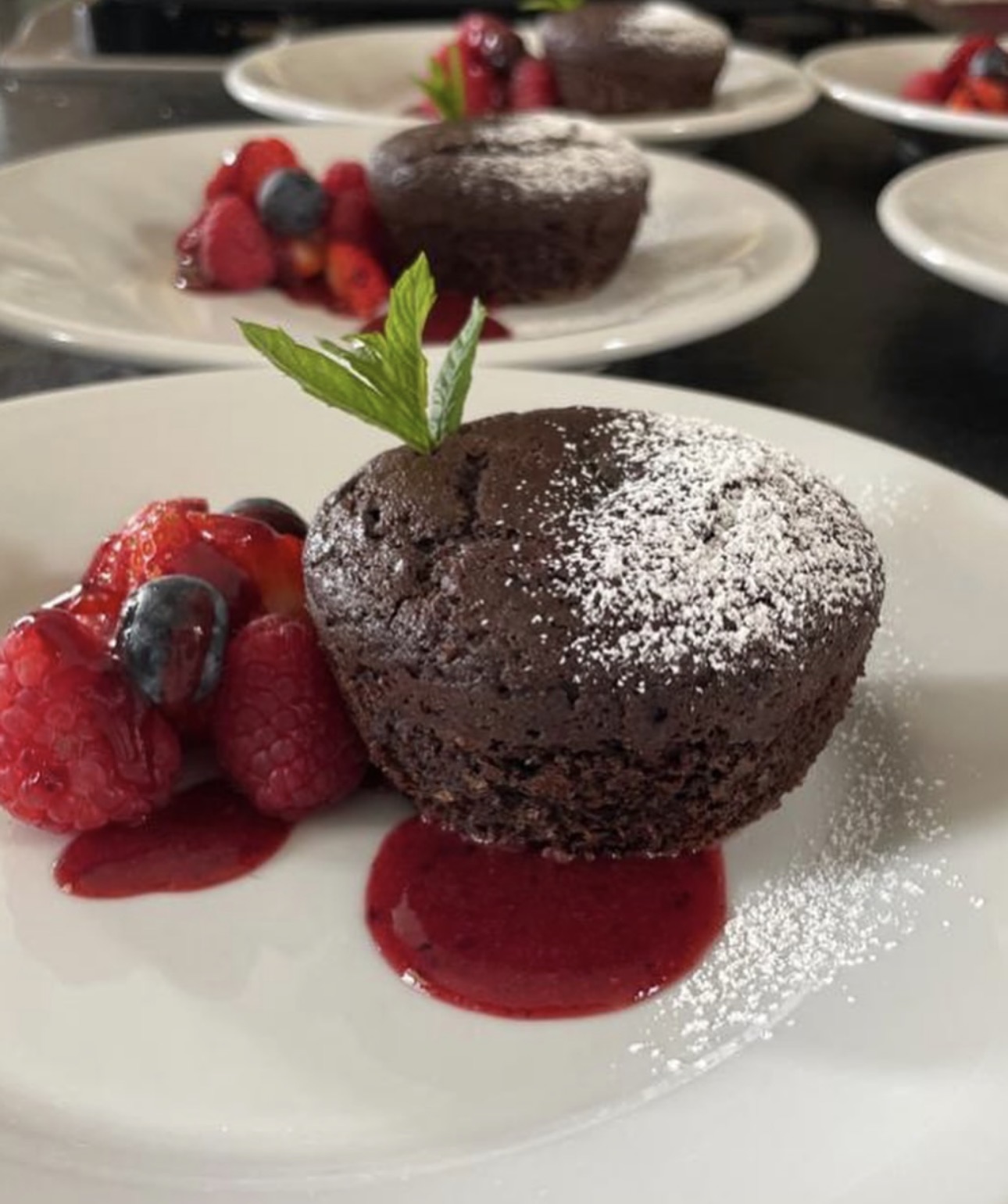 Warm chocolate cake with fresh berries and raspberry sauce, plated for the group