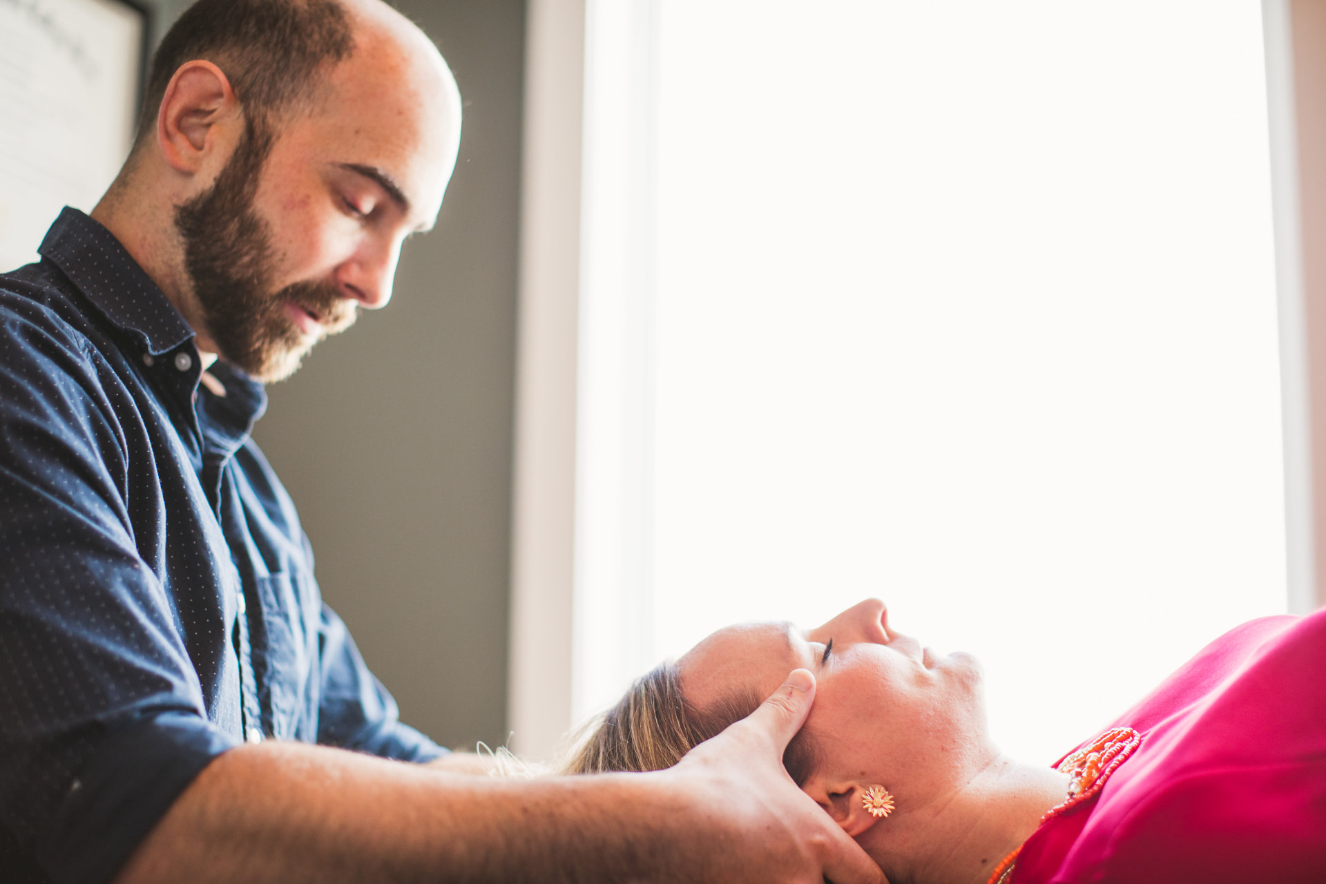 Practitioner performing gentle craniosacral bodywork on a guest's head and neck