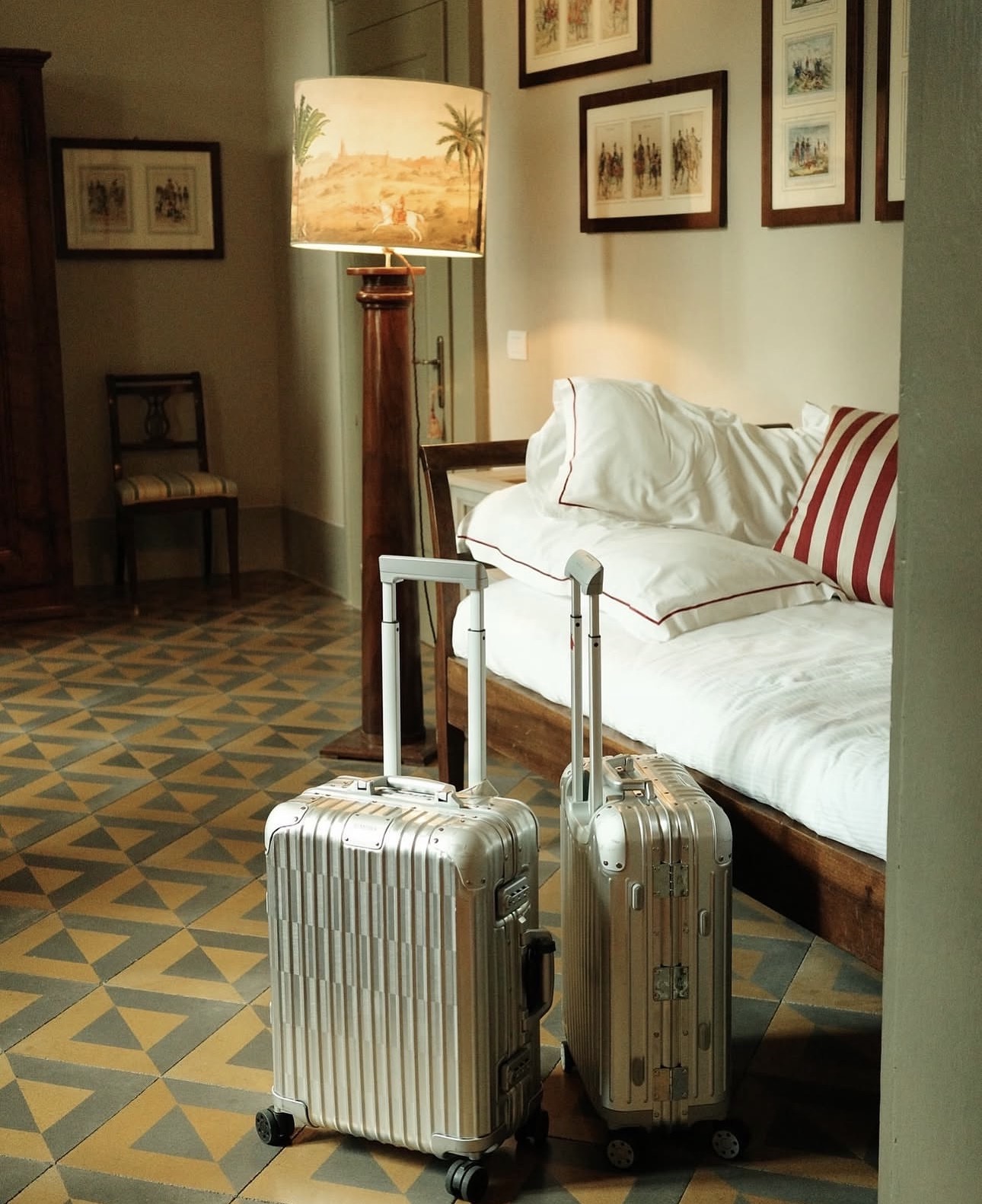 Suitcases beside a linen daybed on patterned tile floors