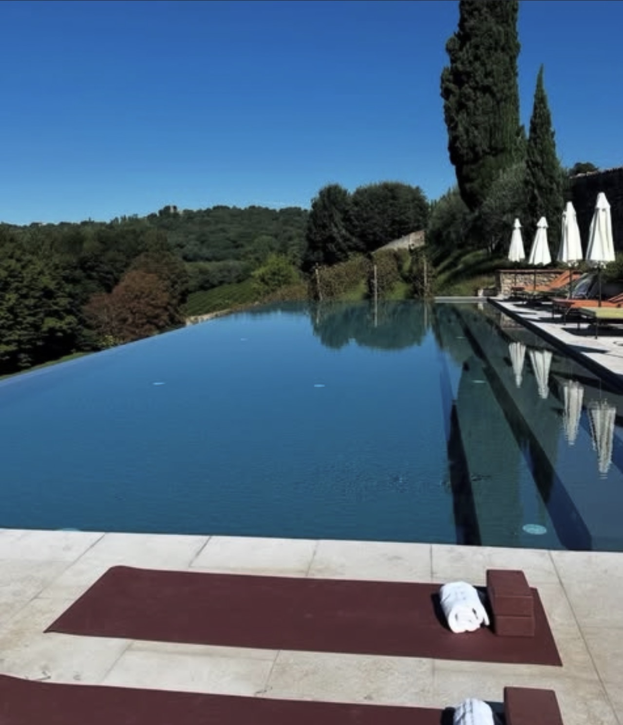 Yoga mats laid out beside an infinity pool overlooking the Franciacorta hills at sunrise